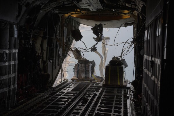  reporters aboard a US military plane watch small batches of aid airdropped on a destroyed Gaza